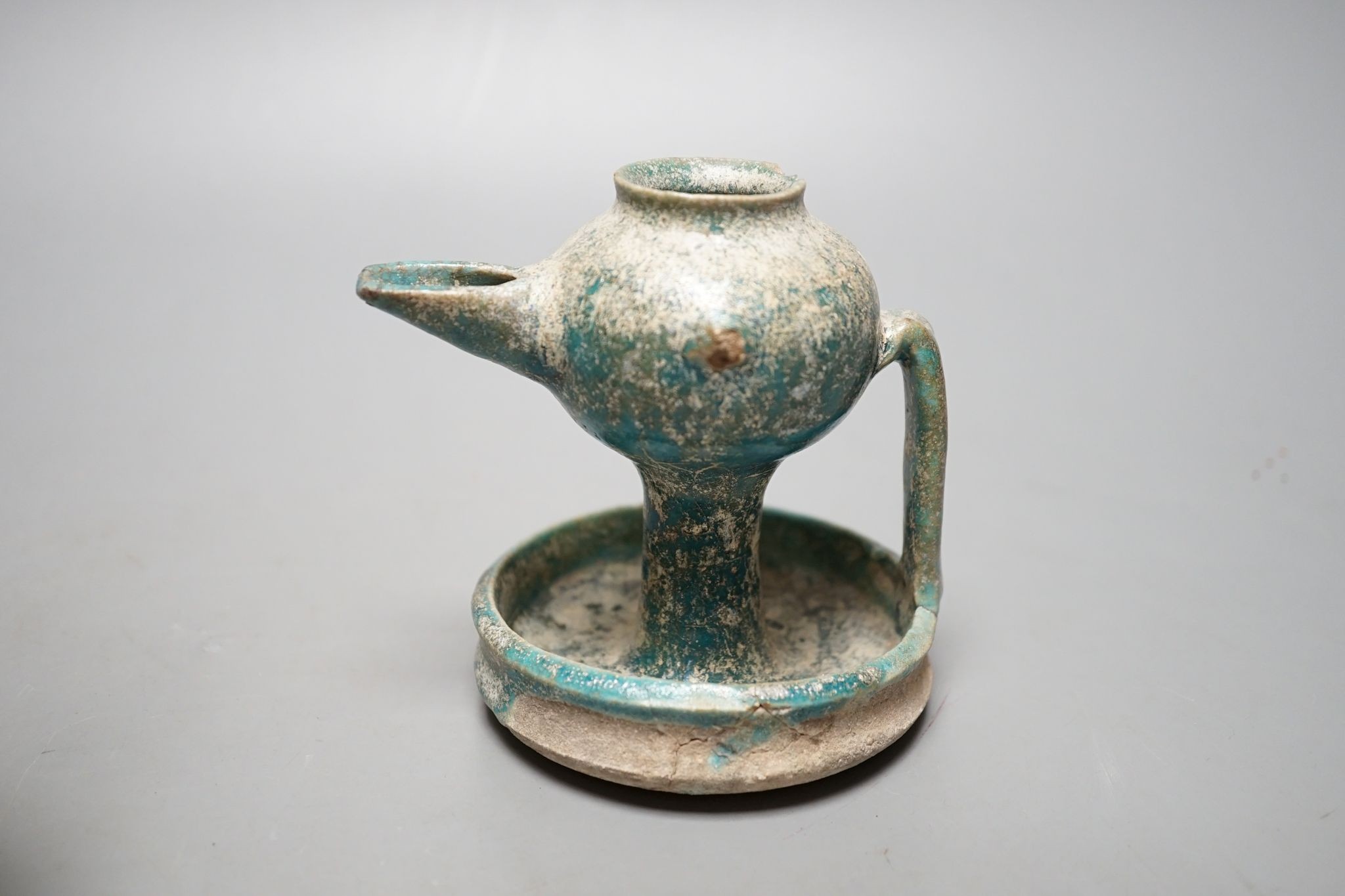 A Kashan oil lamp, 13th/14th century, and an early Islamic glass bottle., Bottle 22 cms high.